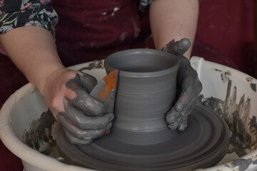 a women creats a vase from clay on a pottery wheel in a pottery 