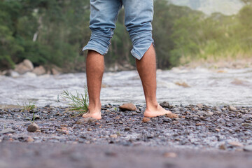 lifestyle. close-up of bare feet of a man on the bank of a rocky river