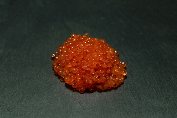 Red trout caviar on a black background.