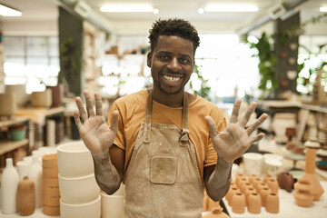 African ceramist with dusty hands smiling in a pottery studio