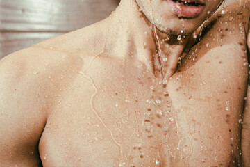 A young attractive guy is washing himself in the shower.