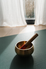 Singing meditation bowl on a yoga mat at home, rainy day relaxation spirituality ritual. 