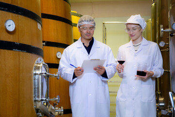 Winemaker team checking and examining producing wine at winery in factory, inspector checking...