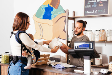 Attendant Introducing Reusable Diapers to a Mother Holding Her Baby in an Eco-Friendly Store