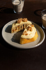 Sliced homemade mixed fruit cinnamon roll with cream cheese frosting and walnuts on top on a ceramic plate