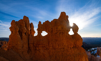 Silhouette of a rock formation in Bryce Canyon Nationalpark in Utah (USA). Bizarre shape with openings and unique outline backlit by the rising sun on a blue sky morning. Tourist attraction and sight. - obrazy, fototapety, plakaty