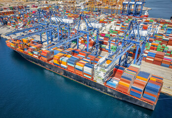 Aerial view of a large container cargo ship being loaded and unloaded in a commercial dock