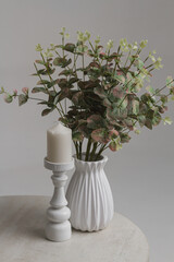 Flowers in a vase and a white candle on a white background