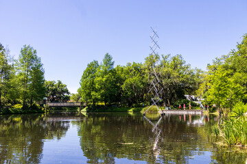 a beautiful spring landscape in the Sculpture Garden at New Orleans City Park with a lake, lush green trees, grass and plants, sculptures, people and blue sky in New Orleans Louisiana USA