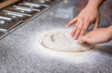 Hands knead the dough for pizza making, flour. Chef preparing pizza dough hands. Pizza dough being rolled and kneaded. Cook hands kneading dough, sprinkling piece of doughs with white wheat flour