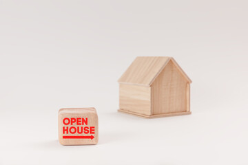 Simplistic wooden house model isolated on pale green background, with text Open House on signboard.
