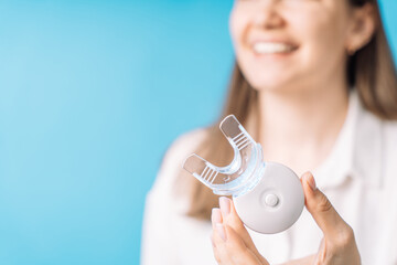Lady holding home teeth whitening equipment.