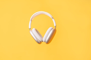 White wireless headphones against a yellow background.