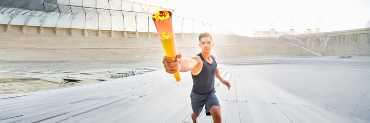 sportsman with torch passing the baton running in a stadium