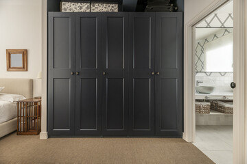 Hallway with a walk-in wardrobe, access to a bathroom with mirrors and marble and a bed with wooden side tables