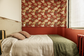 Bedroom with decorative paper on the walls, single bed with wooden headboard upholstered in fabric,...