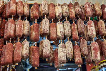 sale of many cured salamis sausages hung in a row at a market in Argentina