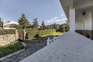 View across the gardens of a house with white balustrades from a long terrace outside terrace