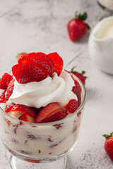 Strawberries with cream in a glass cup on cement table. Copy space.
