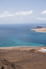Views of the island of La Graciosa from the viewpoint of El Rio. Turquoise ocean. Blue sky with big white clouds. Caleta de Sebo. Town. volcanoes. Lanzarote, Canary Islands, Spain