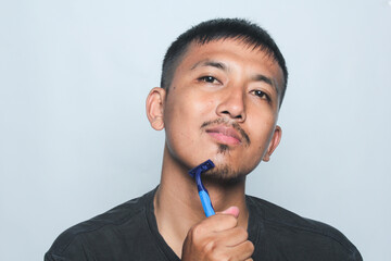 Asian young man being cut off beard and mustache isolated on white background.