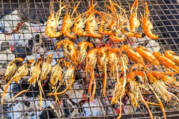 Tasty grilled prawns on wire rack sizzle, exuding smoky allure at a street food stall, promising a tasty, healthful seaside snack to passersby and seafood enthusiasts. Seafood. Wild feasting concept