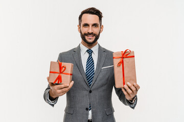 Happy rich businessman in suit holding present boxes isolated over white background. Successful...