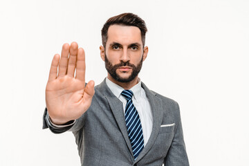 Serious young businessman showing stop gesture with the palm isolated over white background. Angry...
