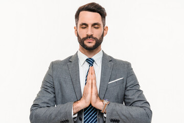 Zen-like young businessman meditating with eyes closed isolated over white background. Concentrated...