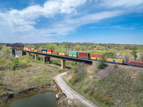 Rulo, NE, USA - April 19, 2024: Container freight train is crossing the Missouri River from Nebraska to Missouri, aerial view.