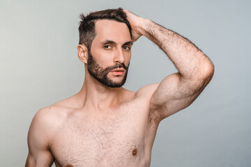 Masculinity concept. Naked handsome young man touching his hair isolated over grey background....