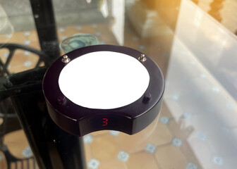 queue pager on restaurant glass table. It is a wireless technology device used to give an audible...