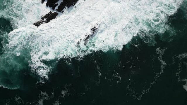 Aerial drone shot of sea waves breaking against cliffs