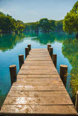 Naklejka premium Dock on Lake Camecuaro Michoacán, Mexico, with its amazing turquoise waters, where the roots of the ahuehuete trees reach the lagoon.