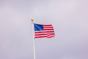 Beautiful view of the American flag waving in the wind against a backdrop of cloudy sky. USA.