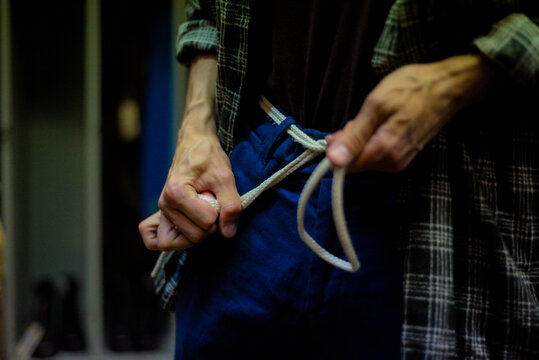 Close-Up of a Man Tying Knot in Dim Light