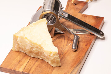 Parmesan cheese on a wooden board with a parmesan grinder