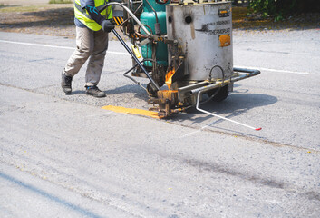 Man use thermoplastic road marking paint machine, hot melt marking paint machinery spraying a...