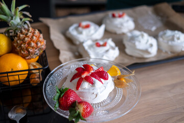 Meringue with strawberries on a clear plate, fruits in background. Ideal for recipe blogs.
