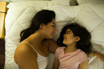 Heartwarming scene capturing a mother and daughter sharing a loving gaze in the comfort of their bedroom at night