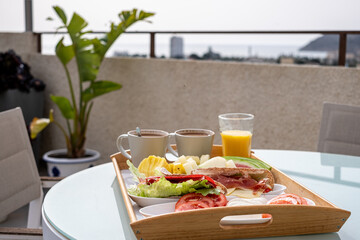 Morning meal served on a balcony overlooking hills, with a full breakfast tray suggesting a...