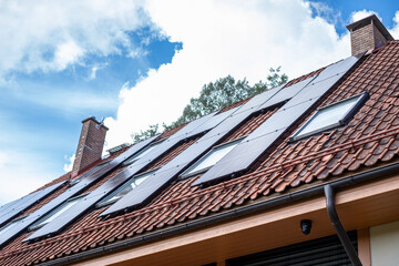 The rooftop solar installation on a family home, set against a backdrop of lush trees and blue skies, showcases a commitment to clean energy and carbon footprint reduction.