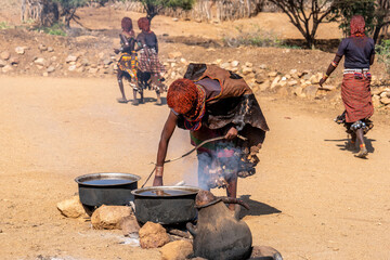 Ethiopia, woman from the Hamer tribe preparers  beverages for the village people.