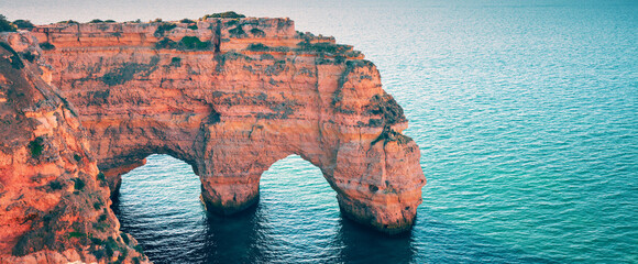 Two arches in the rock. Rock Elephant drinks water. View of Praia da Marinha and Benagil beach in...