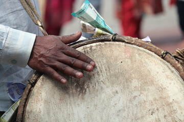An Indian male drummer beats on a drum near the Durga Temple. Ritual drum and hand close-up.