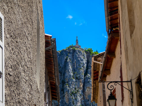 Walking in medieval charming street with view of Chapelle Notre Dame du Roc Church on a hill overlooking the town of Castellane in Alpes de Haute Provence in France. Close to Gorge du Verdone