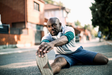 Active young black man stretching on the street