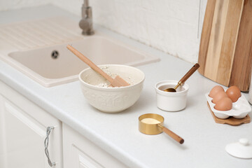 Home kitchen interior.Bowl with dough and spatula, eggs and bowl of sugar on kitchen table in modern kitchen.