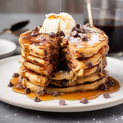 
delicious fluffy chocolate chip pancakes with the topping of butter and sugar syrup on a plate with a slice cut out in kitchen