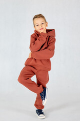 Little boy in hip hop dance position.Little boy model. Little boy in brown tracksuit on white background.